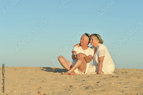 Happy elderly couple sitting on tropical beach