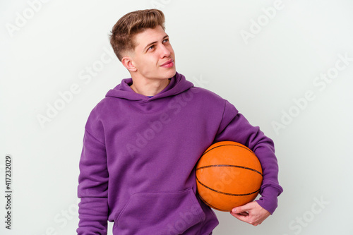 Young caucasian man playing basketball isolated background dreaming of achieving goals and purposes