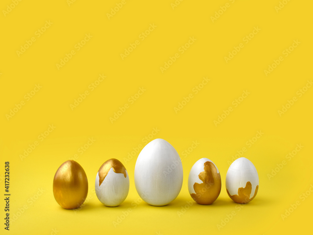 Minimalist Easter composition. Golden paint pouring eggs in row on yellow background. Greeting trendy color concept with copyspace. Minimalist Easter composition. Golden paint pouring eggs in row on yellow background. Greeting trendy color concept with copyspace.