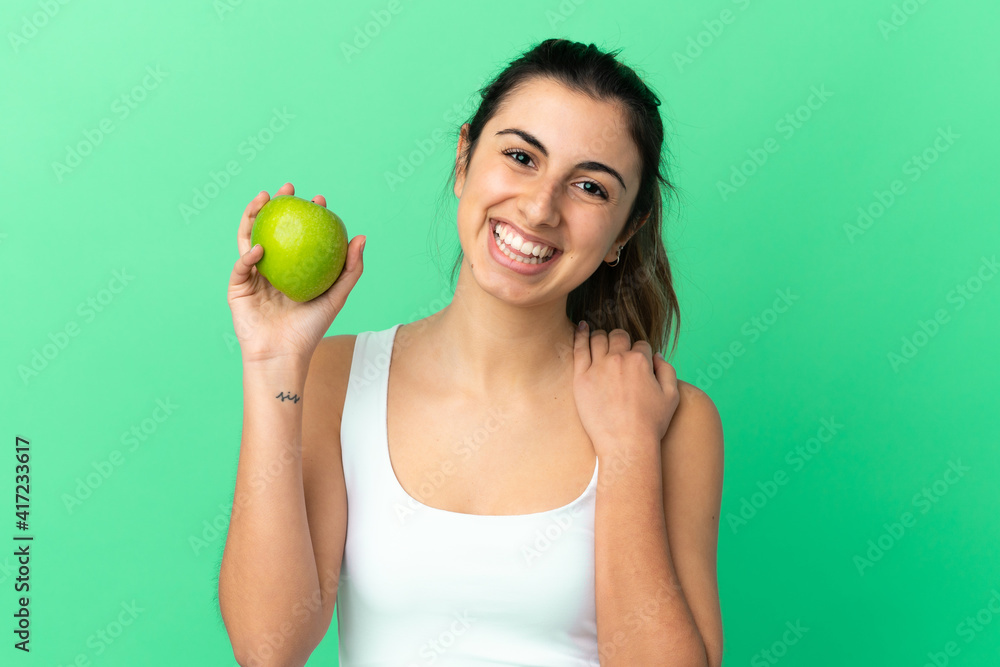 Young caucasian woman isolated on green background with an apple and happy Young caucasian woman isolated on green background with an apple and happy