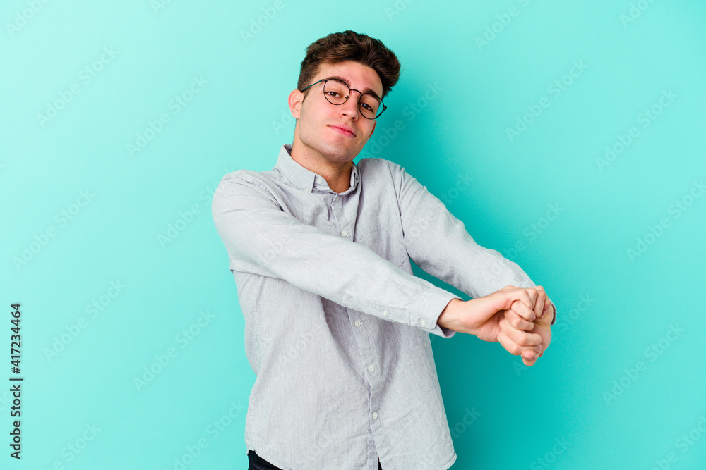 Young caucasian man isolated on blue background stretching arms, relaxed position. Young caucasian man isolated on blue background stretching arms, relaxed position.