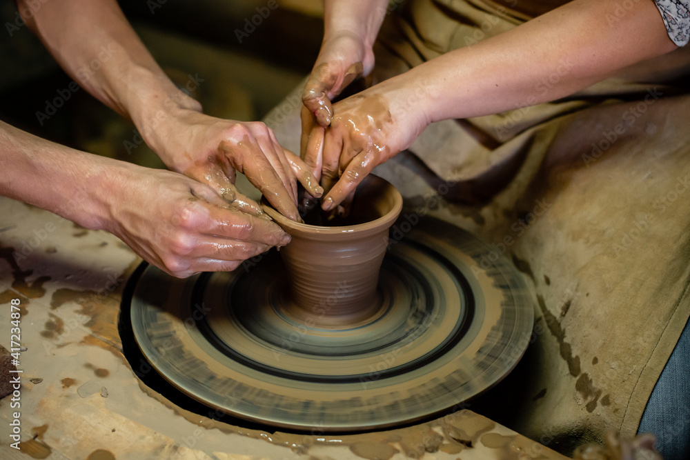 Pottery classes, student making clay pot on wheel. Close-up of dirty hands, sculpting clay crockery pottery training
