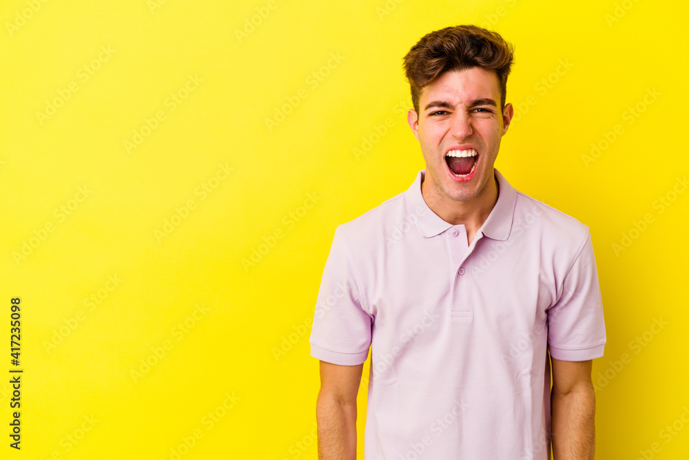 Young caucasian man isolated on yellow background shouting very angry, rage concept, frustrated. Young caucasian man isolated on yellow background shouting very angry, rage concept, frustrated.