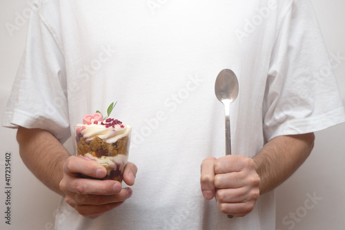 Trifle portioned mini cake with a spoon in hand. Layered trifles dessert with sponge cake, whipped cream and chocolate.