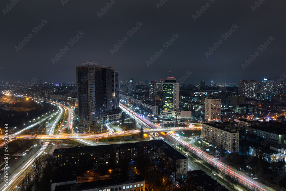 Aerial panoramic drone above roof view of Kiev night traffic road junction scene. Highway city at evening car light trails. Scenic urban skyline cityscape. Busy downtown life of Ukraine capital