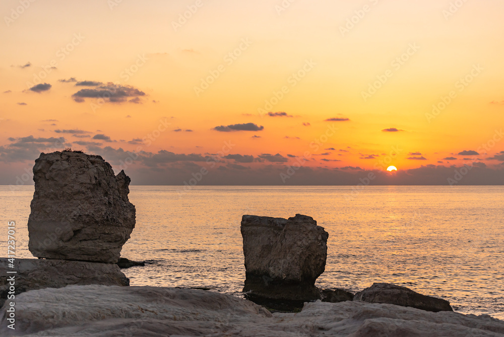 Sunset draws a sunny path on the sea among the rocks.