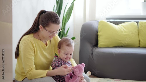 Authentic close up shot of young mother show body parts nose, eyes on teddy study with newborn baby on mat floor home. infant, maternity, motherhood, parenthood, childhood, life, authenticity photo