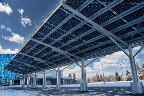 A modern solar carport for public vehicle parking is outfitted with solar panels producing renewable energy. photo
