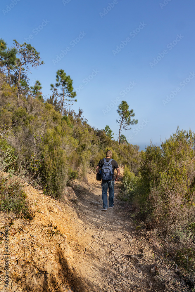 A man with a backpack goes hiking in the mountains of Theoule-sur-Mer city on the Mediterranean coast of France.