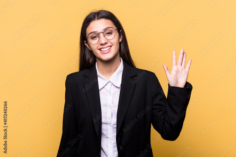 Young Indian business woman isolated on yellow background smiling cheerful showing number five with fingers. Young Indian business woman isolated on yellow background smiling cheerful showing number five with fingers.