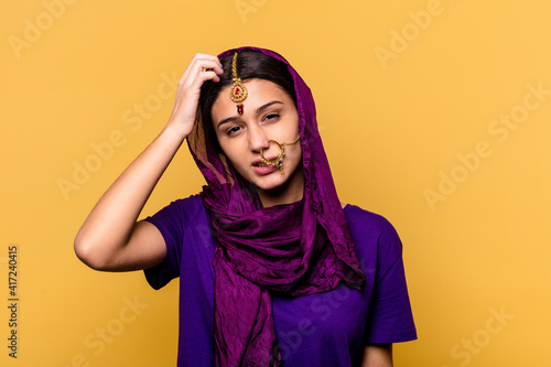 Young Indian woman wearing a traditional sari clothes isolated on yellow background being shocked, she has remembered important meeting. © Asier