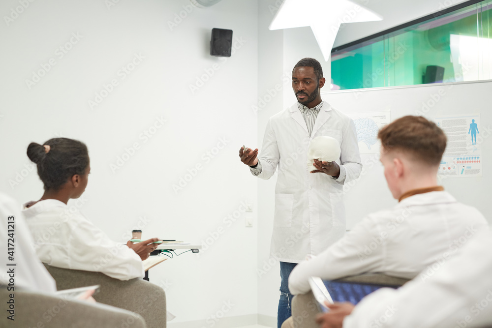 Portrait of African-American man standing by whiteboard while giving seminar on medicine in college, copy space Portrait of African-American man standing by whiteboard while giving seminar on medicine in college, copy space