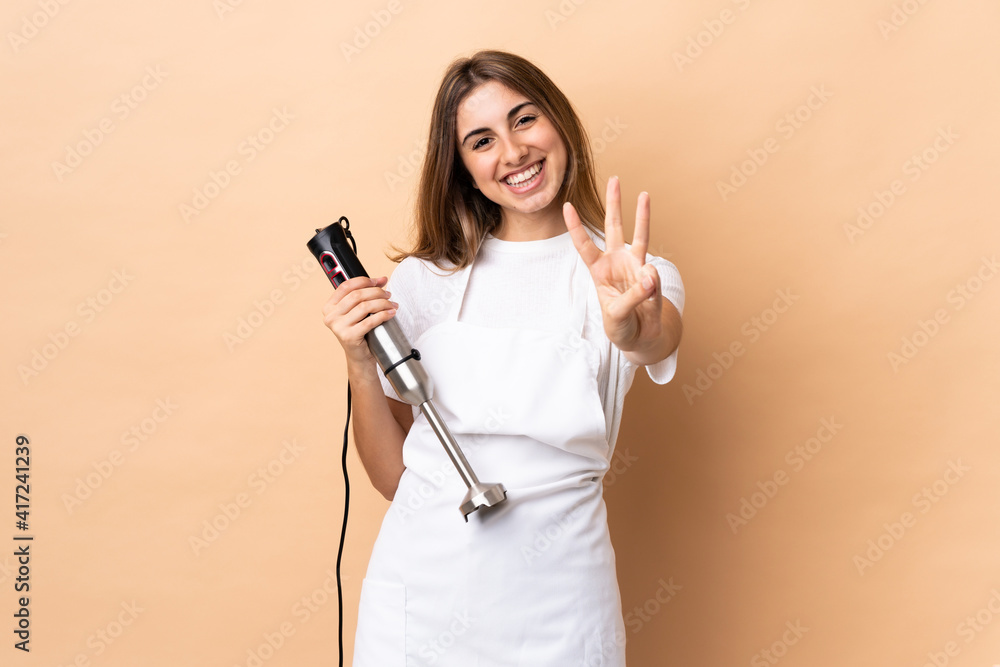 Woman using hand blender over isolated background happy and counting three with fingers Woman using hand blender over isolated background happy and counting three with fingers