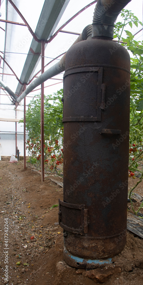 wood burning old stove in a tomatoes greenhouse. wood burning old stove in a tomatoes greenhouse.