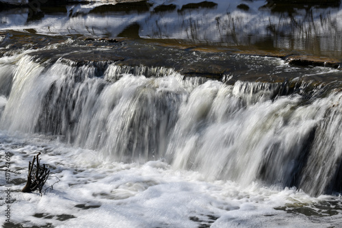 Waterfall splashing over river rocks in winter