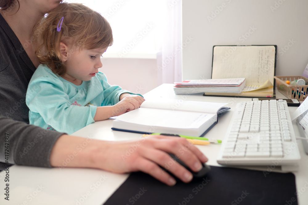 Mother multi-tasking, holding girl kid and using computer at home. Candid authentic and real life mom working and parenting. Mother multi-tasking, holding girl kid and using computer at home. Candid authentic and real life mom working and parenting.