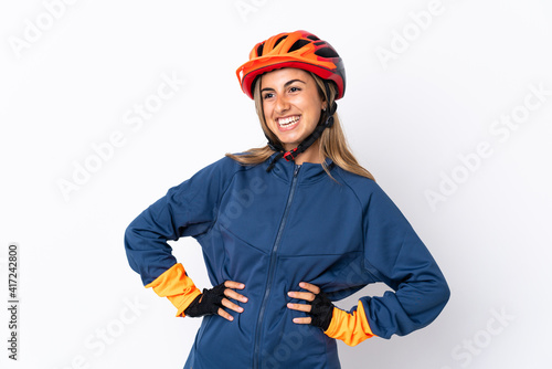 Young hispanic cyclist woman isolated on white background posing with arms at hip and smiling