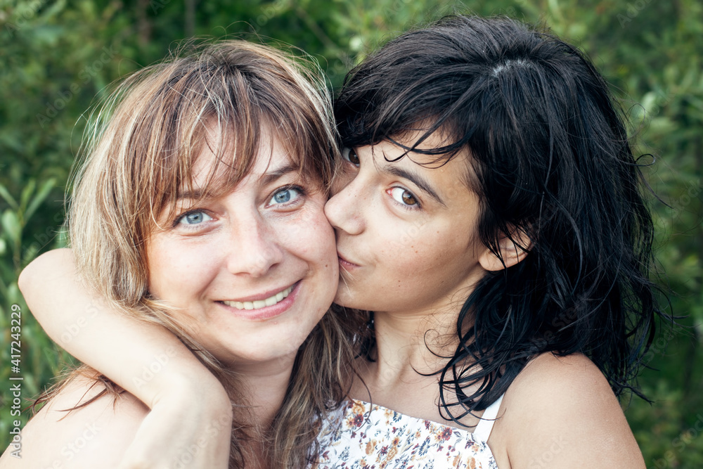 Obraz premium Portrait of woman in kissing her daughter outdoor.