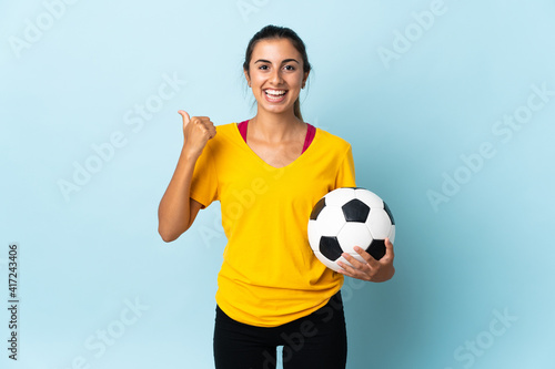 Young hispanic football player woman over isolated on blue background pointing to the side to present a product © luismolinero