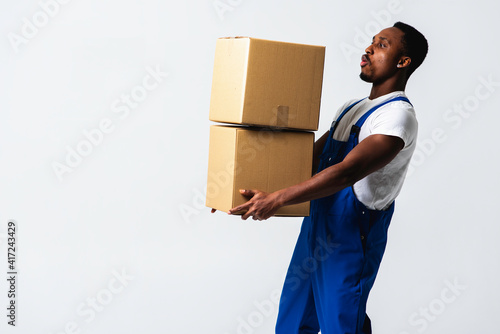 courier with a paper box, a young African American man in a blue jumpsuit and a white T-shirt holding craft paper boxes for sending. Isolated on a white background. The concept of delivery, mail, ship