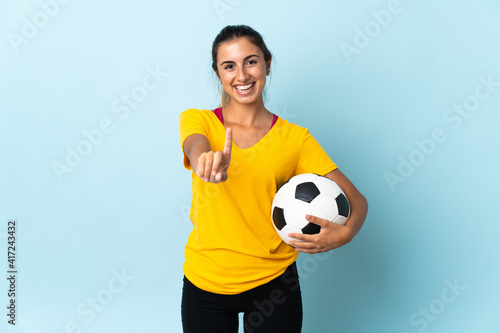 Young hispanic football player woman over isolated on blue background showing and lifting a finger © luismolinero