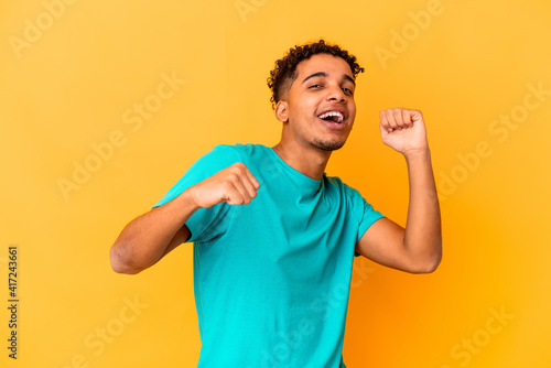 Young african american curly man isolated on purple dancing and having fun.