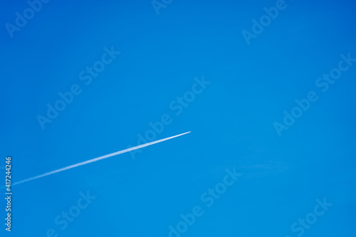 A trail from the plane in the blue clear sky.
