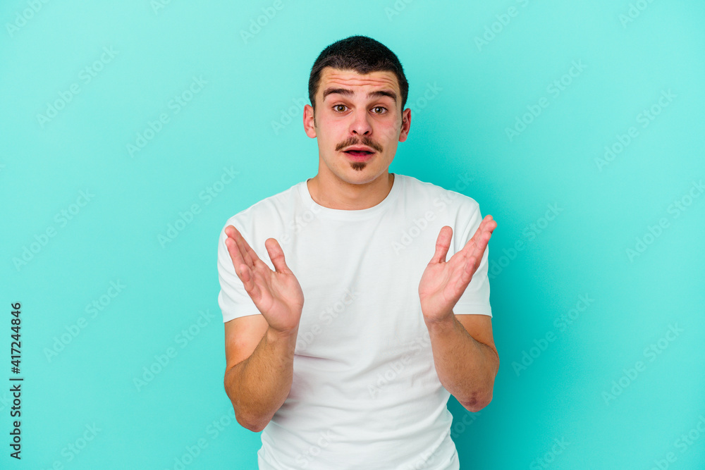 Fototapeta premium Young caucasian man isolated on blue background surprised and shocked.