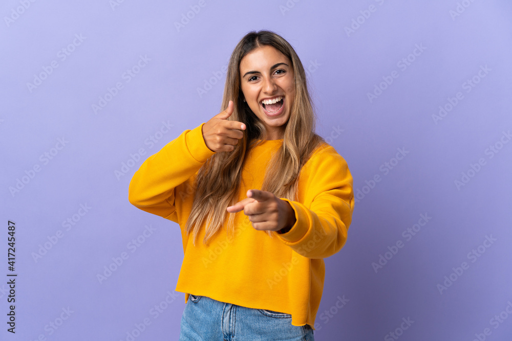 Young hispanic woman over isolated purple background pointing to the front and smiling Young hispanic woman over isolated purple background pointing to the front and smiling