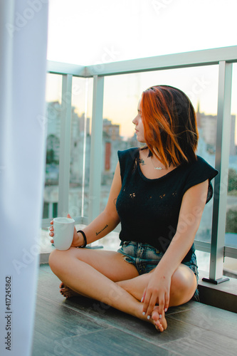 retrato de joven mujer tomando un café en el balcón de su casa 