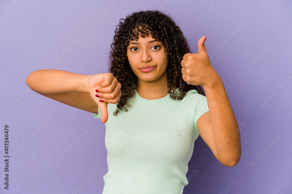 Young african american afro woman isolated showing thumbs up and thumbs down, difficult choose concept Young african american afro woman isolated showing thumbs up and thumbs down, difficult choose concept