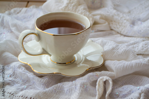 Antique porcelain tea cup full of tea on white vintage background
