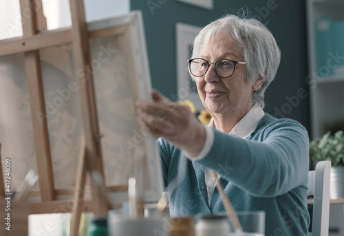 Happy senior lady looking at her finished artwork