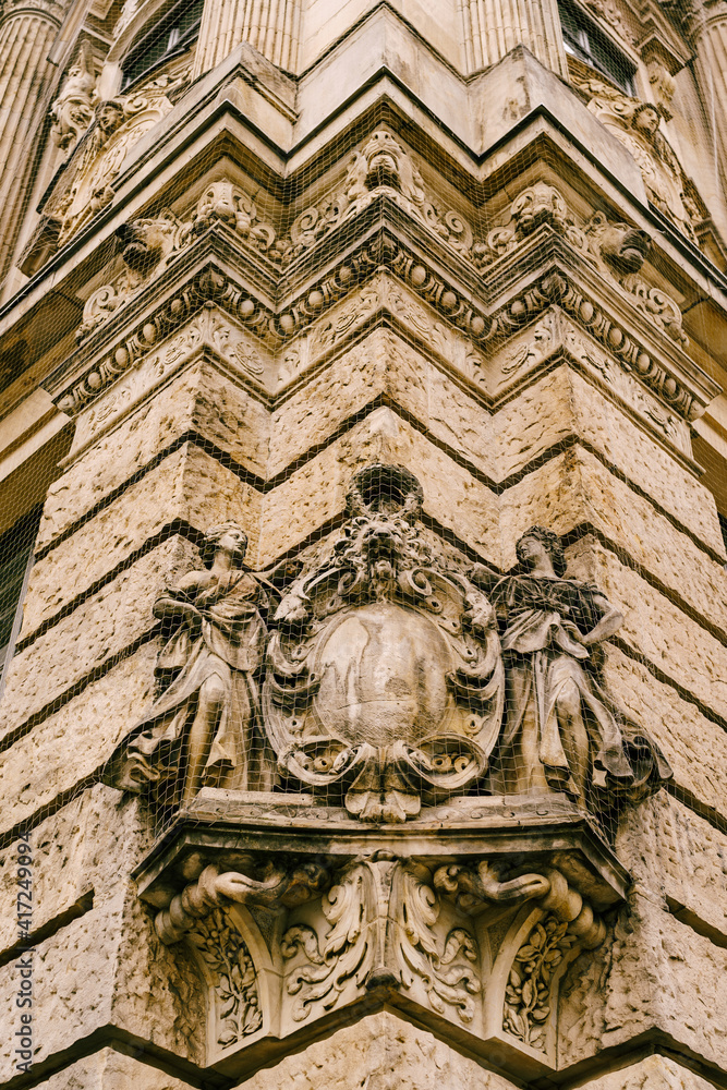 Gothic art in the form of high relief with figures of women and a lion's face on the wall of an ancient building