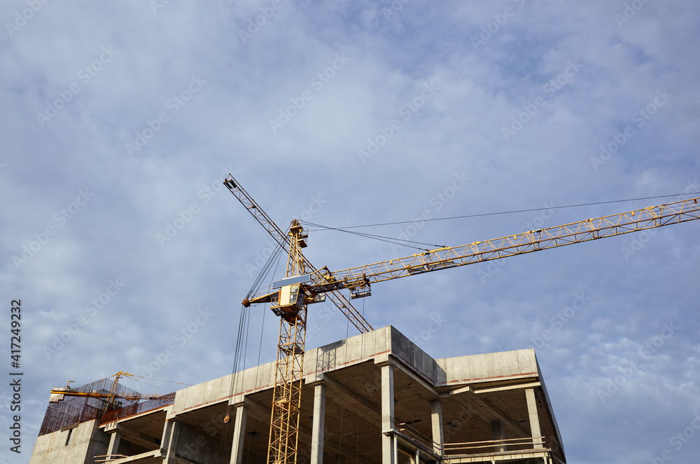 Tower crane building a house. Concrete building under construction Tower crane building a house. Concrete building under construction