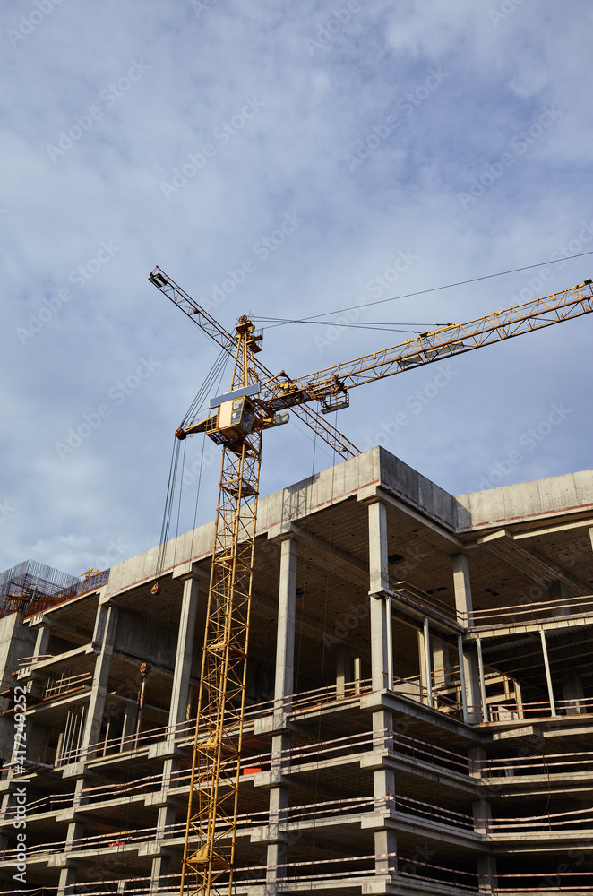 Tower crane building a house. Concrete building under construction Tower crane building a house. Concrete building under construction