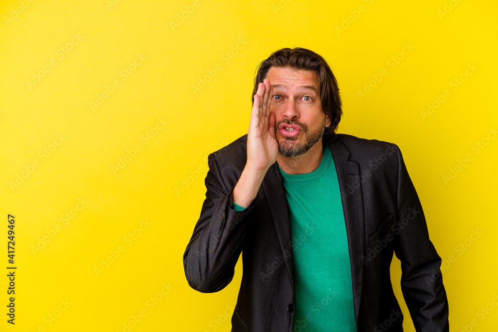 Middle age caucasian man isolated on yellow background is saying a secret hot braking news and looking aside Middle age caucasian man isolated on yellow background is saying a secret hot braking news and looking aside