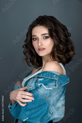 close-up portrait of young sexy brunette woman with serious facial expression sideways to the camera in white underwear and denim jacket