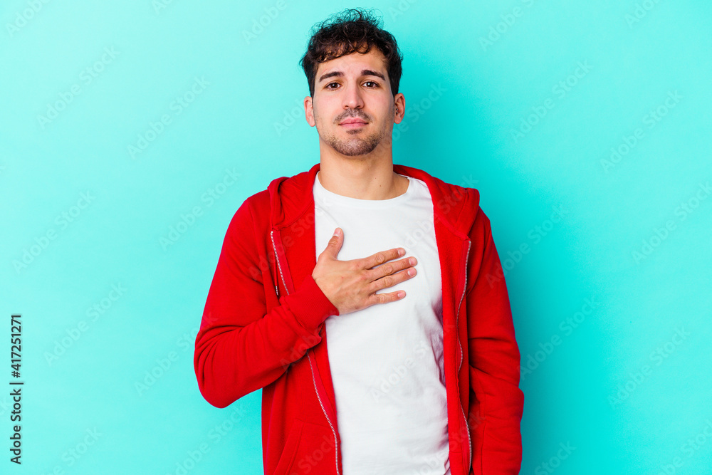 Young caucasian man isolated on blue background taking an oath, putting hand on chest. Young caucasian man isolated on blue background taking an oath, putting hand on chest.