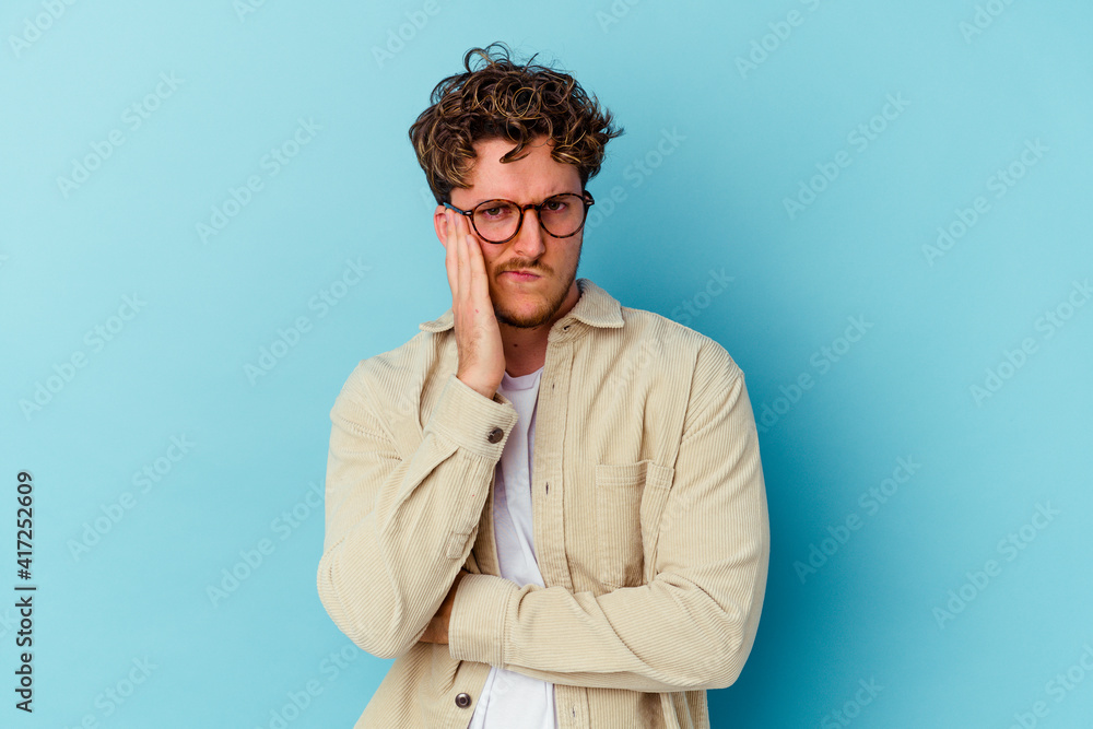 Fototapeta premium Young caucasian man wearing eyeglasses isolated on blue background blows cheeks, has tired expression. Facial expression concept.