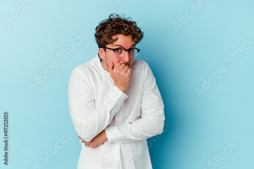 Young caucasian business man isolated on blue background scared and afraid.