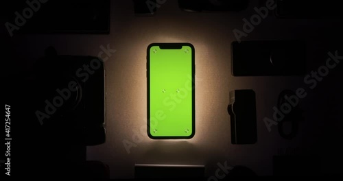 Chroma key, green screen closeup shot of a phone, a smartphone with slow, smooth zoom in. Tech app mockup in dark investment with light illumination. Display with tracking markers. Gadgets layout grid