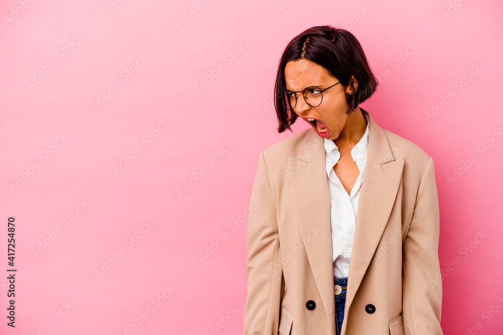 Young business mixed race woman isolated on pink background shouting very angry, rage concept, frustrated. Young business mixed race woman isolated on pink background shouting very angry, rage concept, frustrated.