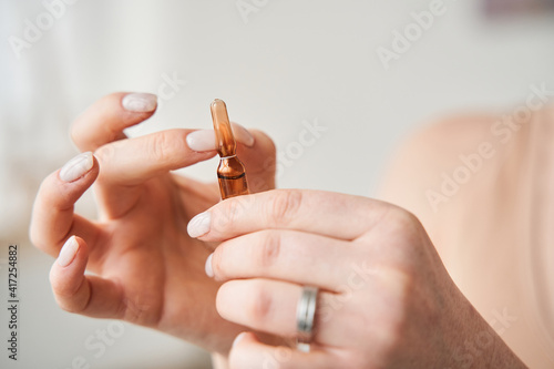 Woman snaps fingers at ampoule before opening