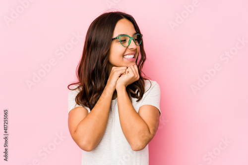 Young mixed race hispanic woman isolated keeps hands under chin, is looking happily aside. © Asier