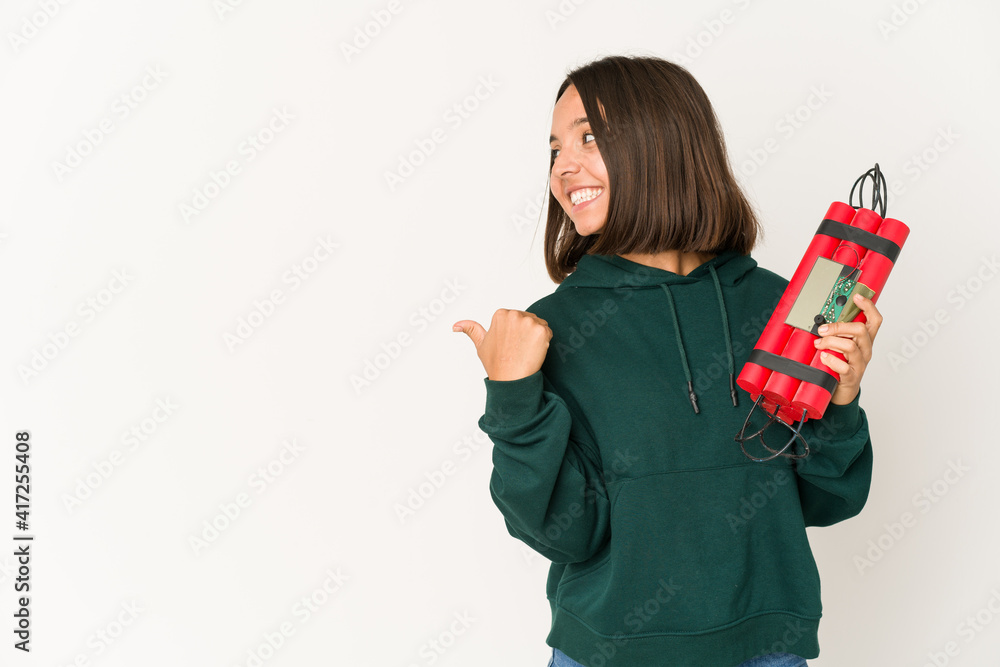 Young hispanic woman holding dynamite points with thumb finger away, laughing and carefree.