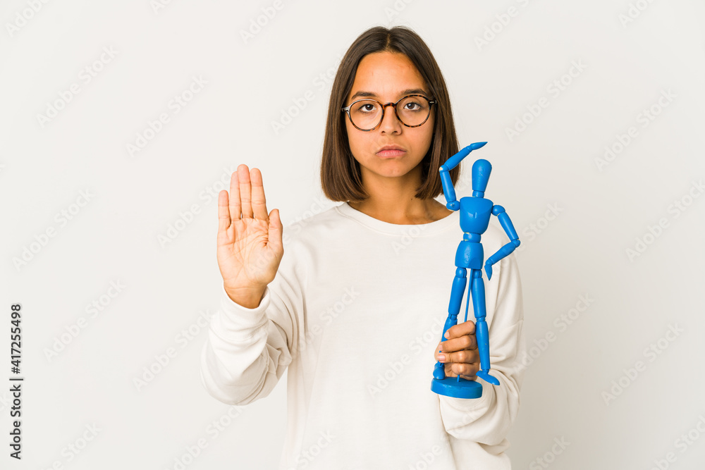 Young hispanic mixed race woman holding a wood doll standing with outstretched hand showing stop sign, preventing you. Young hispanic mixed race woman holding a wood doll standing with outstretched hand showing stop sign, preventing you.