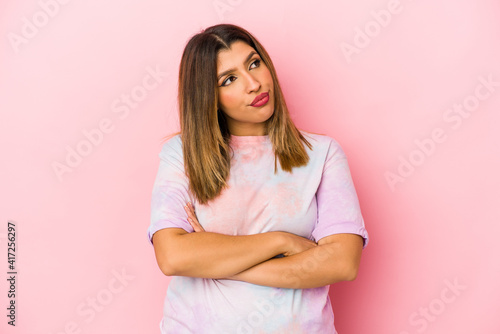 Young indian woman isolated on pink background dreaming of achieving goals and purposes