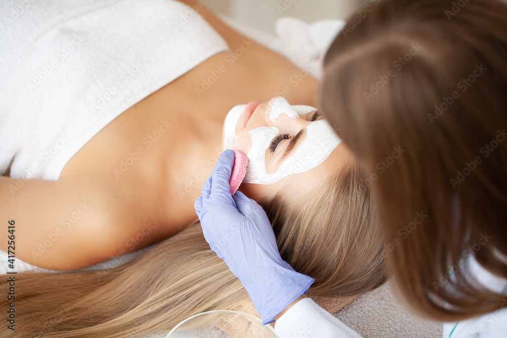 Naklejka premium Spa Woman applying Facial cleansing Mask, Beauty Treatments
