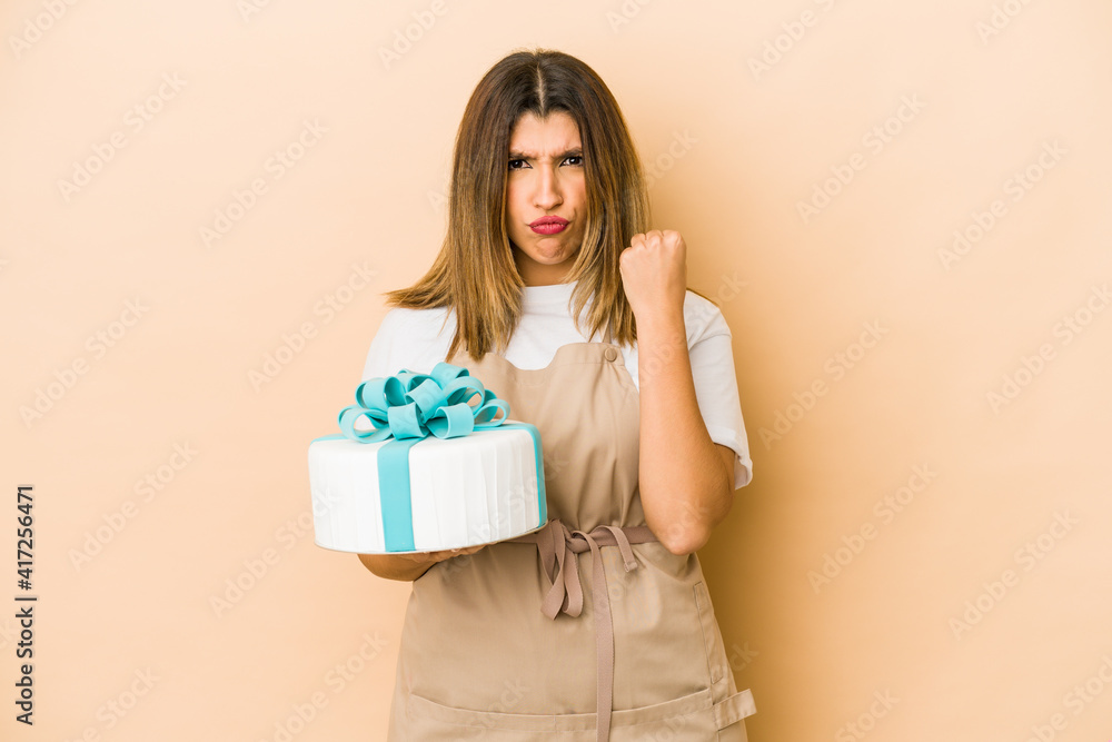 Young indian pastry chef woman isolated showing fist to camera, aggressive facial expression.